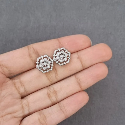 Floral stud earrings with circular crystal cluster, shown on open palm