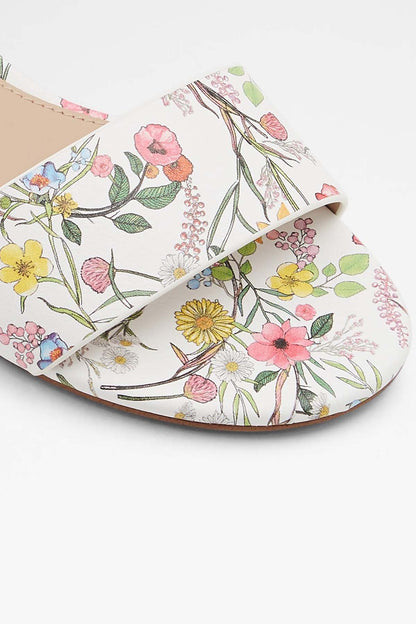 White floral flat sandal with open toe and cutout strap, close-up of printed upper