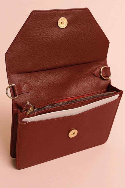 Burgundy leather satchel-style bag with top flap, round coin clasp, and strap