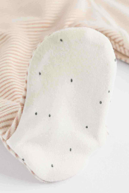 White fabric baby footed romper with small dotted detail and curved toe