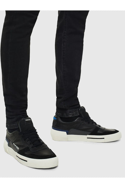 Black Diesel sneakers on legs with white midsoles and blue side accents