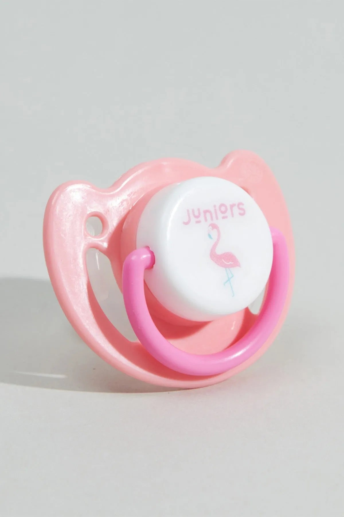 Pink silicone pacifier with flamingo print, heart-shaped guard, angled view