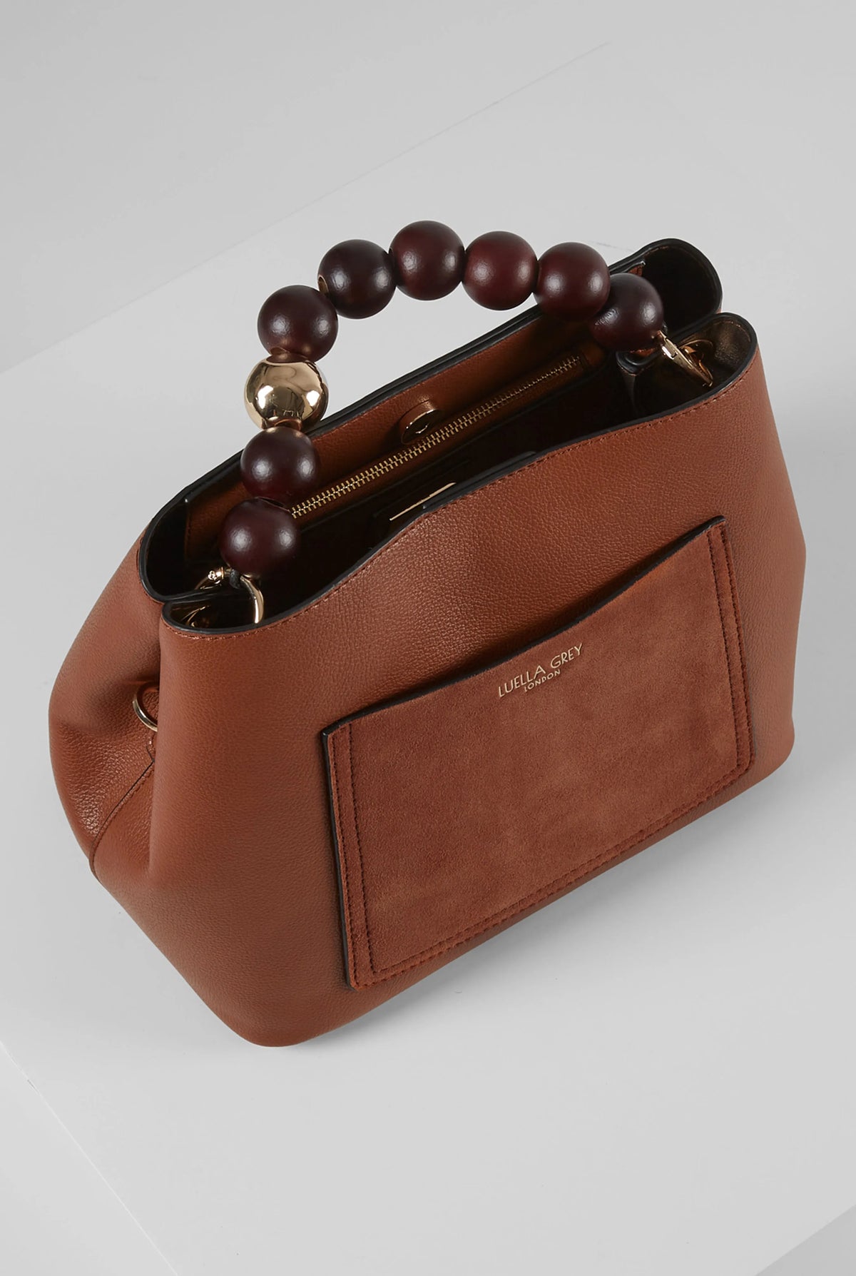 Brown leather handbag with beaded handle, top zipper, and front patch pocket.
