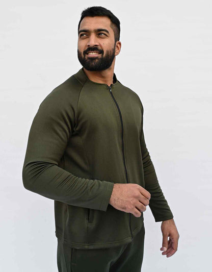 Bodybrics men's olive zip-up jacket and matching pants set, angled front view with one hand holding cuff