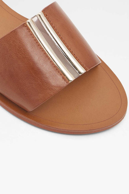 Brown leather slide sandal close-up: gold metal bar on stitched toe strap