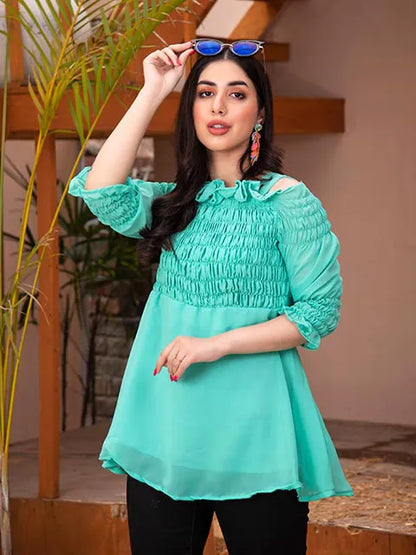 Turquoise smocked tunic top with ruffled neckline and sleeves; close-up front with black leggings