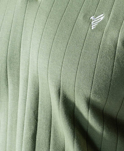 Green ribbed polo fabric close-up with small white chest logo