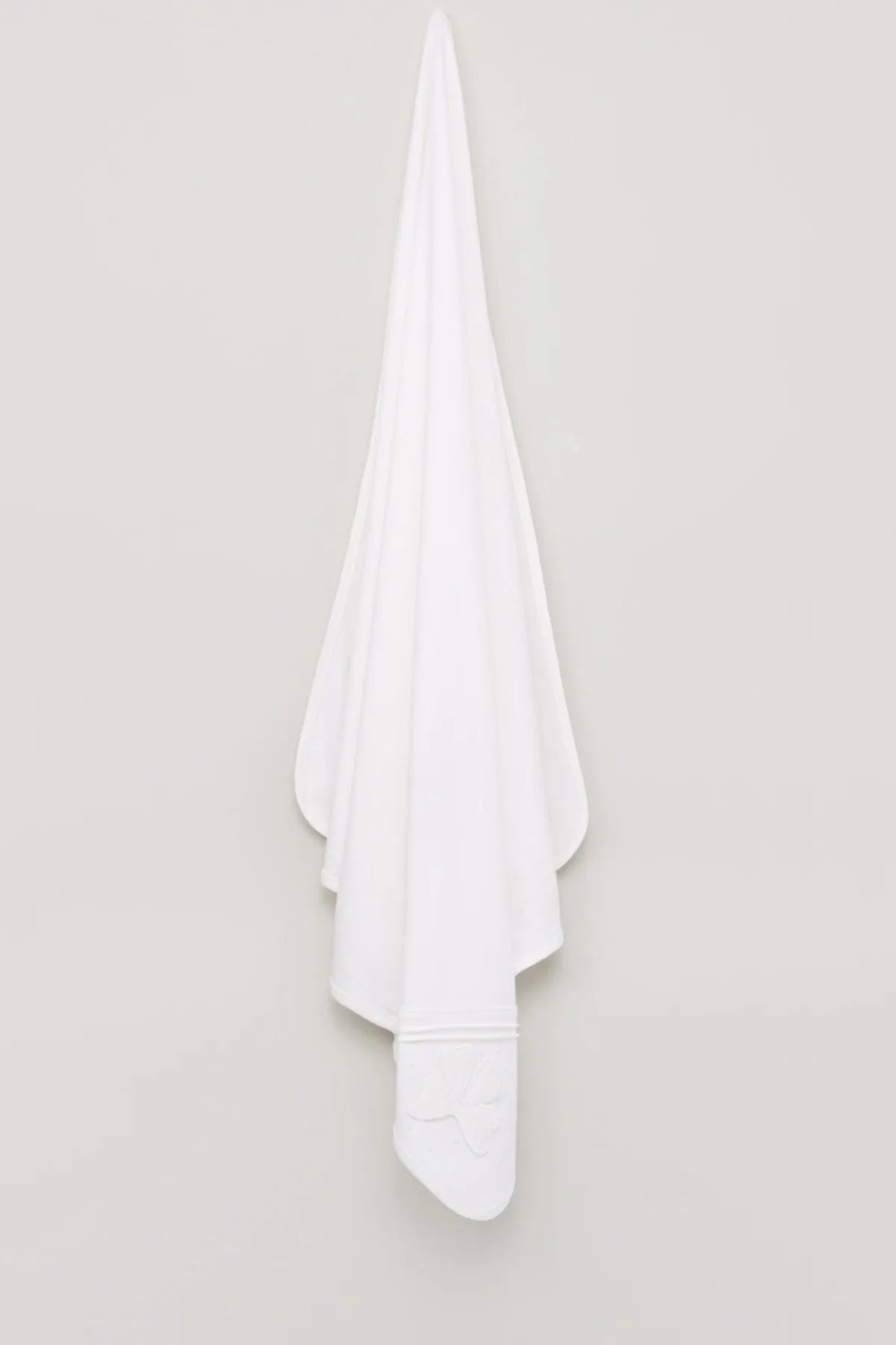 White baby blanket draped with rounded edge and small stitched motif