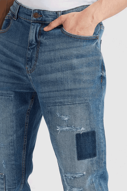 Blue denim jeans close-up: embroidered yoke, distressed thigh and knee, patch pocket