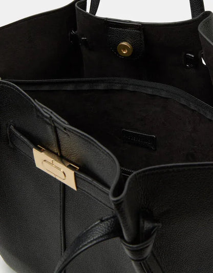 Black tote bag interior view with gold clasp and zip pocket on outer panel