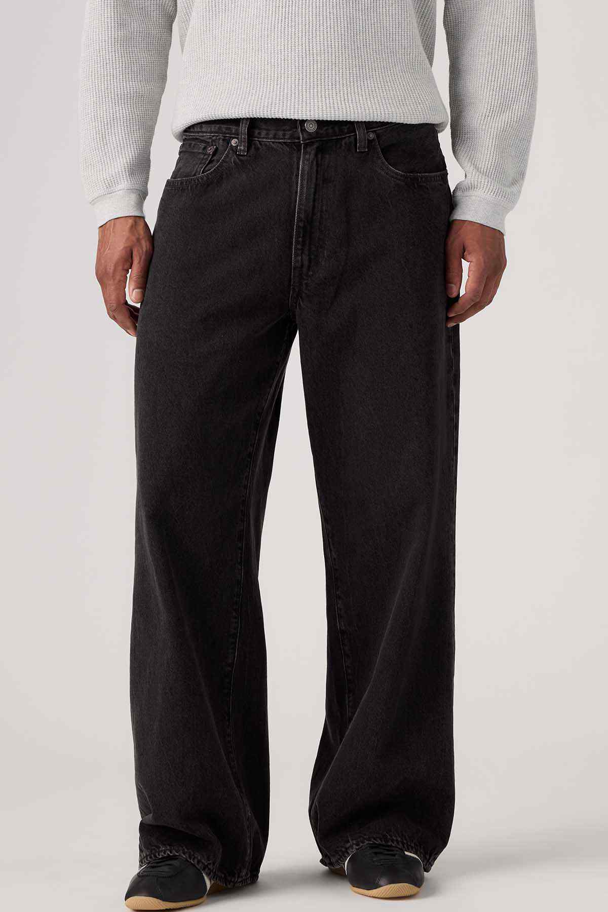 Black denim jeans close-up: belt loops, button closure, wide straight legs