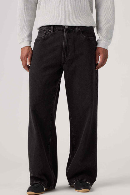 Black denim jeans close-up: belt loops, button closure, wide straight legs
