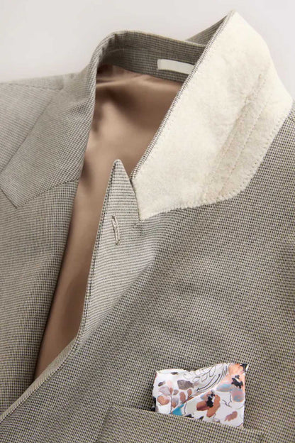 Men's gray blazer inside view with cream lining and interior chest pocket, close-up.
