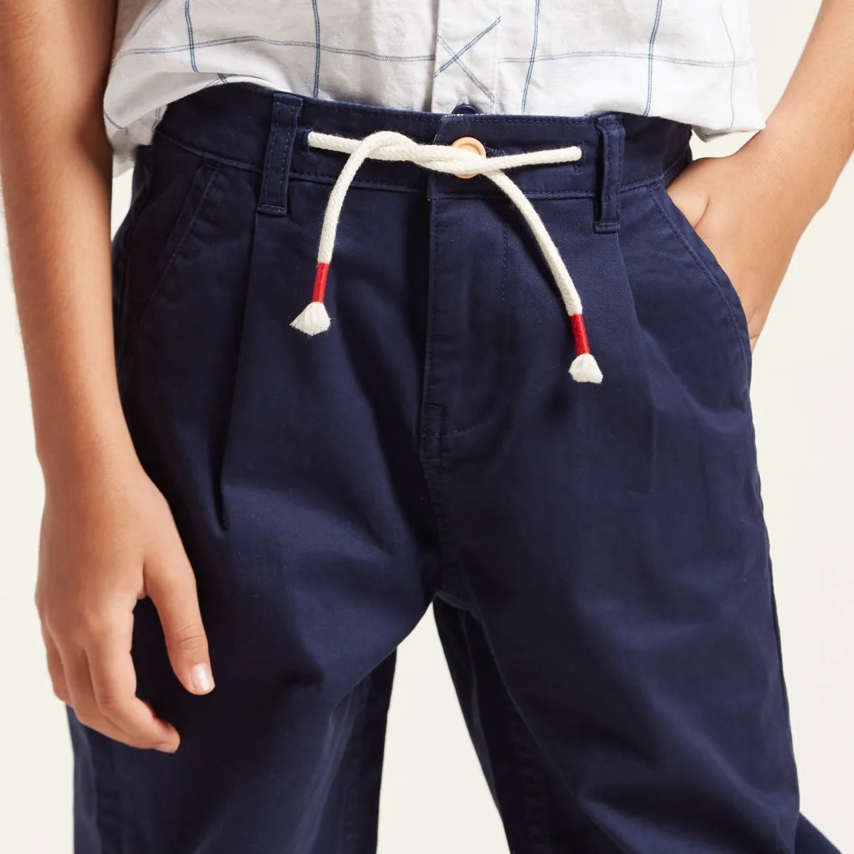 Navy blue pants with drawstring waist and side pockets, red and white cords