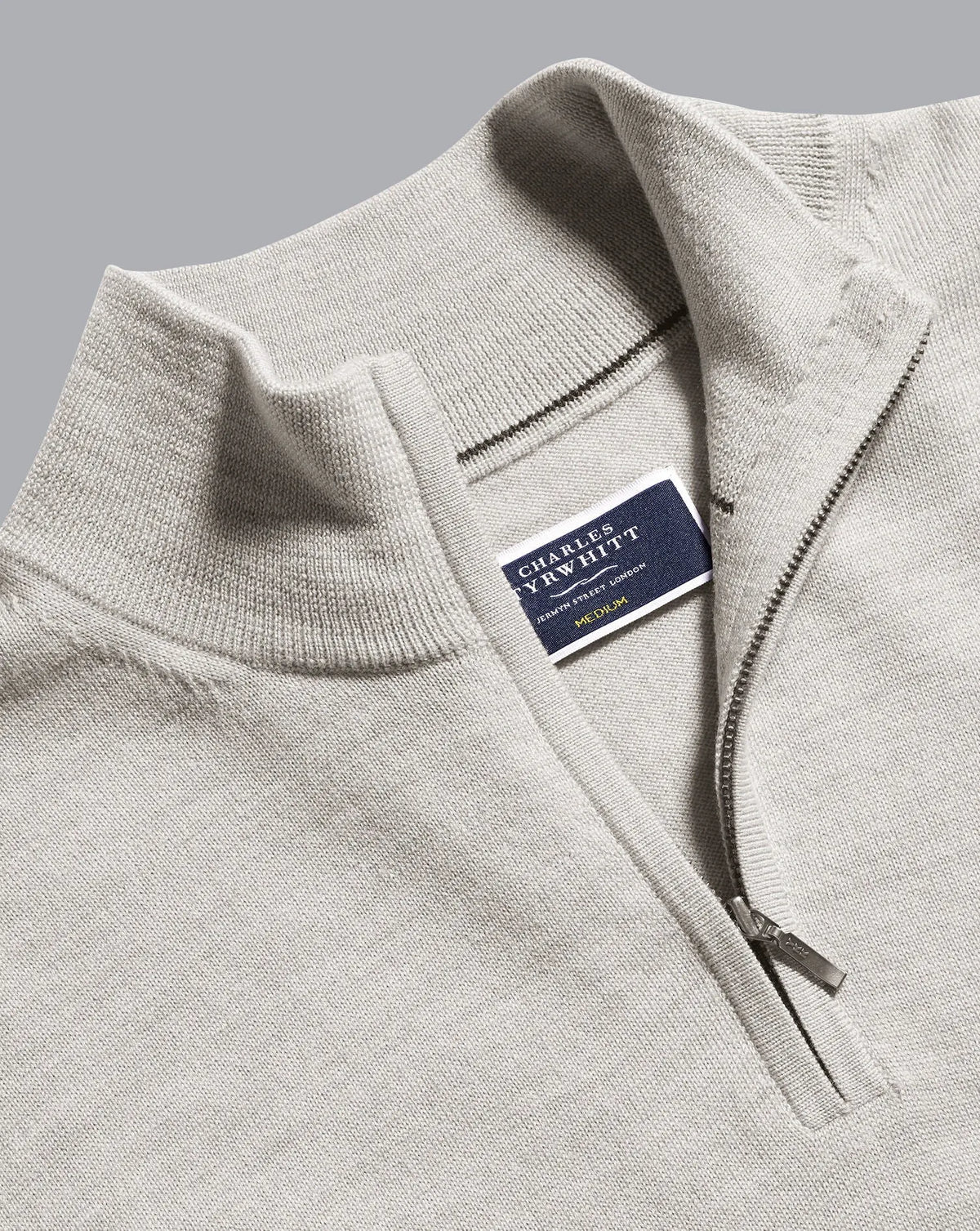 Grey knit sweater close-up of zip and brand label