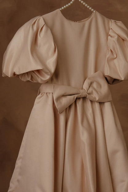 Beige dress close-up: puff sleeves, fitted bodice, and waist bow tie