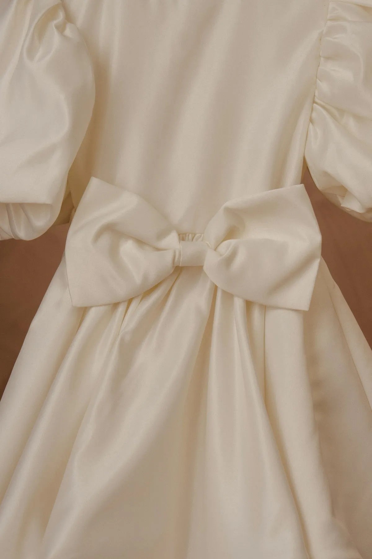 White dress close-up: large satin waist bow with gathered bodice
