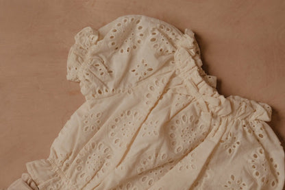 Cream eyelet puff-sleeve blouse close-up with gathered seams and yoke