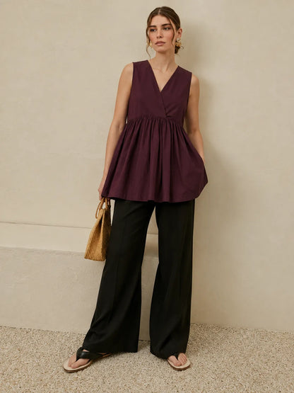 Maroon sleeveless V-neck peplum top with gathered waist and flowing skirt