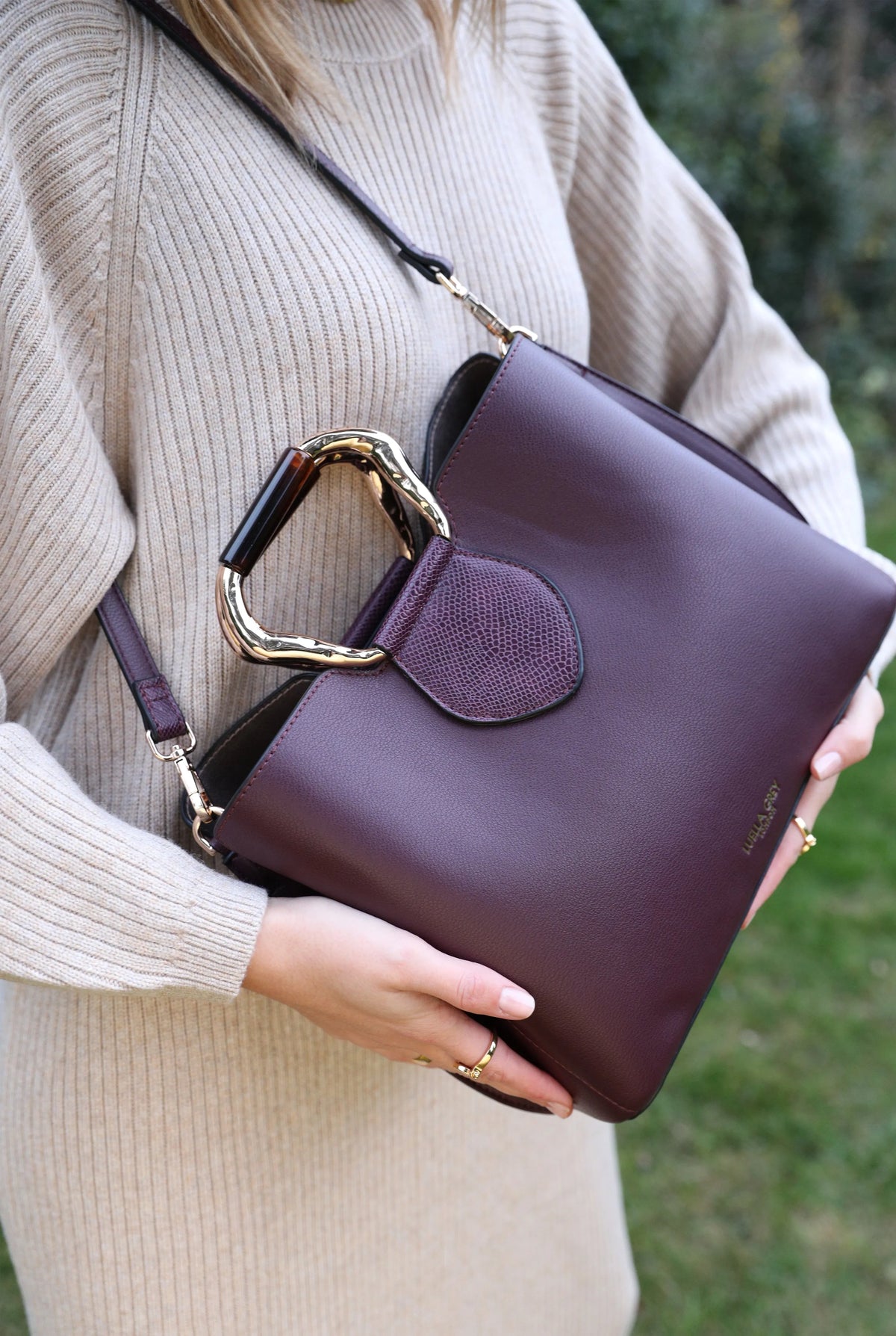 Dark purple structured handbag with gold-tone handle hardware and front flap pocket