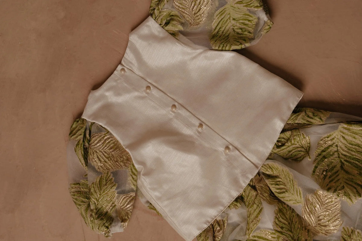 White button-up shirt with gold buttons, paired with green leaf print fabric