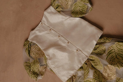 White button-up shirt with gold buttons, paired with green leaf print fabric