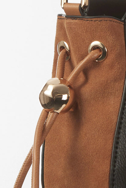 Tan suede panel crossbody bag with gold-tone ring hardware and braided drawstring