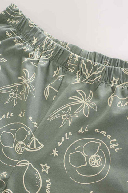Sage green pajama fabric with white illustrated fruit, leaves, and stars