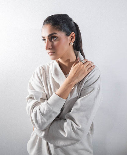 Fitted off-white hoodie with hood and long sleeves, model hands at collar