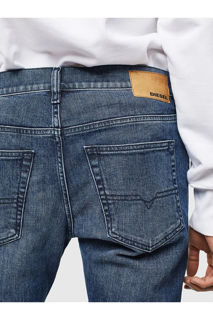 Blue denim jeans back waistband with tan logo patch and stitched pockets