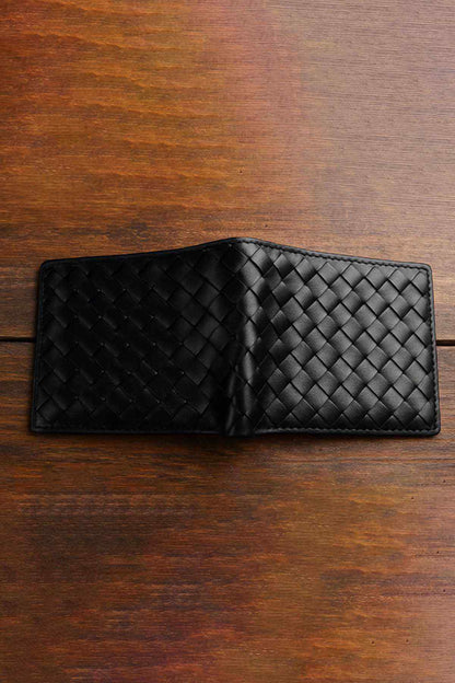 Black woven leather bi-fold wallet with center seam, open layout on wood