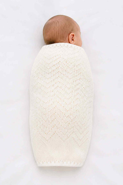 Baby shawl in white knit, back view with openwork pattern