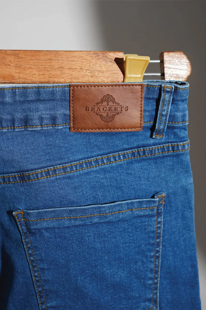 Blue denim jeans close-up with leather brand patch and buttoned front pocket