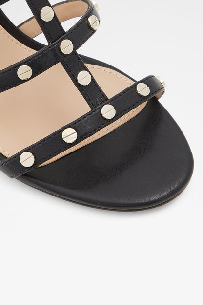 Close-up of black studded sandal straps with round metal rivets and tan footbed
