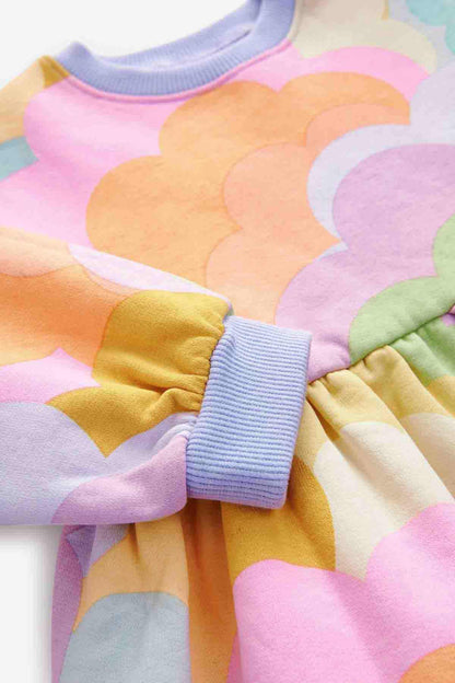 Close-up of multicolor cloud-print dress with striped cuffs and gathered hem