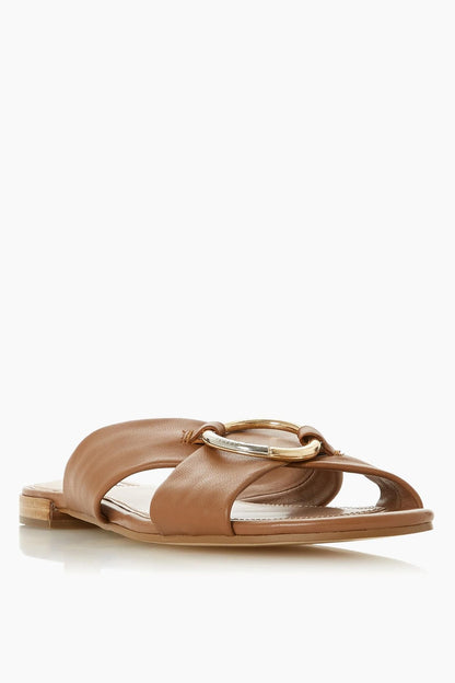 Tan leather slide sandals with open toe, circular metal buckle, flat sole
