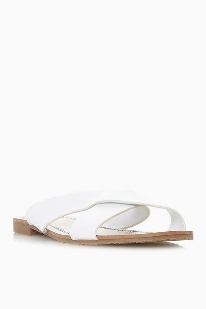 Dune London white slide sandals with crossover straps and rhinestone trim, tan sole.
