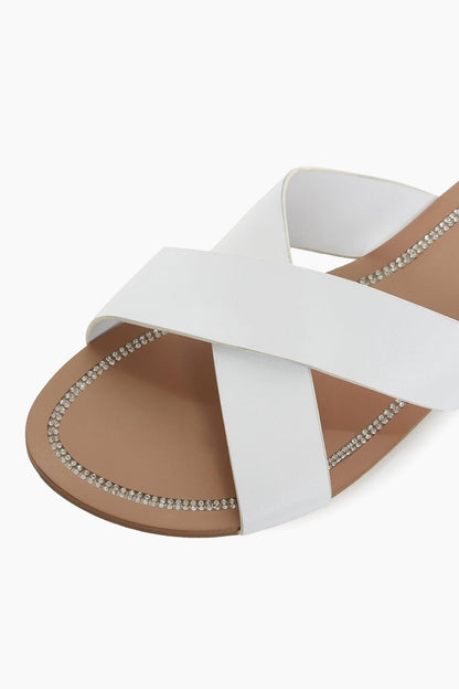 Dune London white slide sandals, tan sole, rhinestone chain edging on straps.