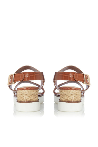 Tan leather sandals with two straps, buckles, and jute-wrapped platform