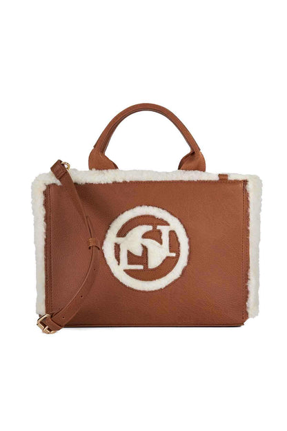 Brown handbag with white shearling sides, front logo patch and adjustable shoulder strap