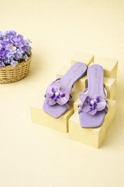 Pair of purple flat sandals with flower appliques and slingback straps
