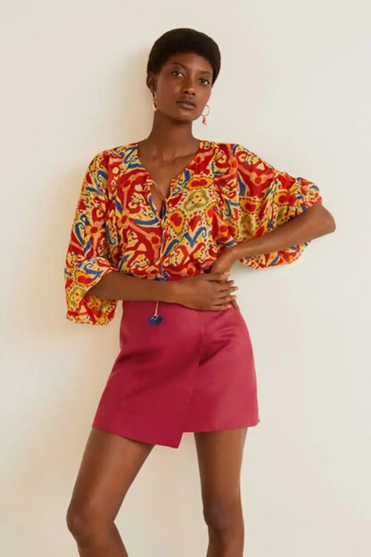 Multicolor patterned blouse with wide sleeves and button-front, worn with red mini skirt