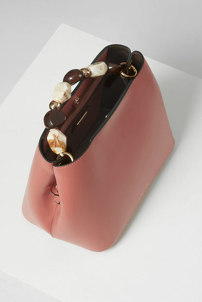 Pink handbag side view with beaded handle and top zip closure