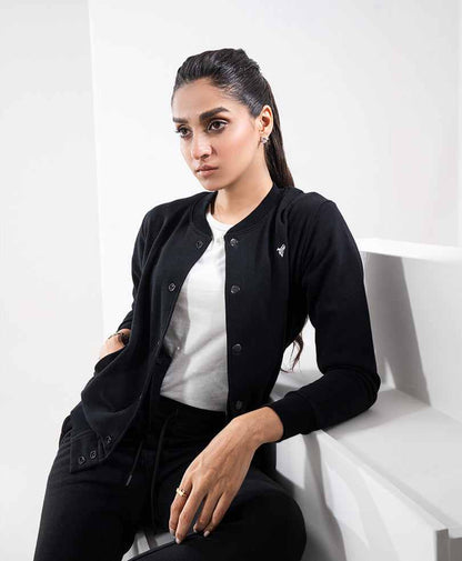 Black button-front fitted jacket with long sleeves and chest logo, worn over a white top