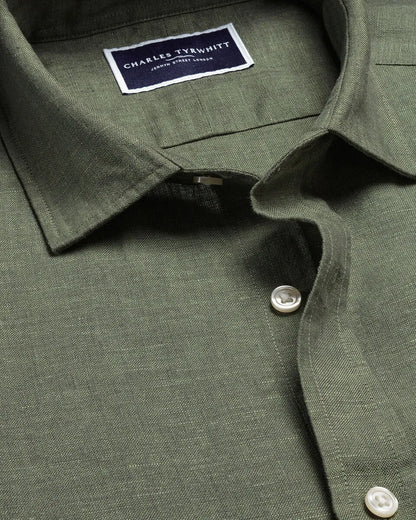 Green linen shirt detail with brand label, buttoned front placket and collar
