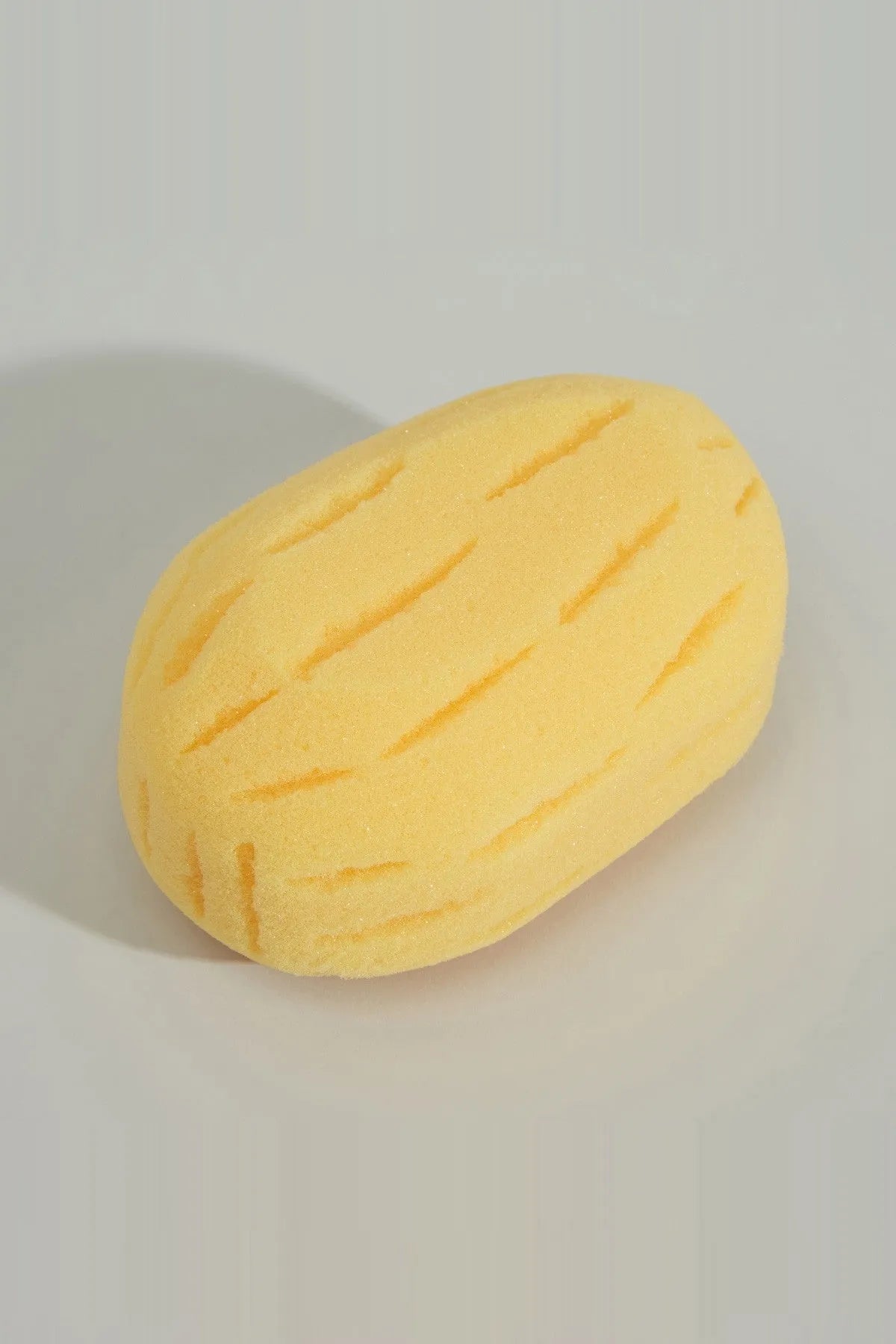 Yellow bath sponge, oval shape with raised diagonal grooves