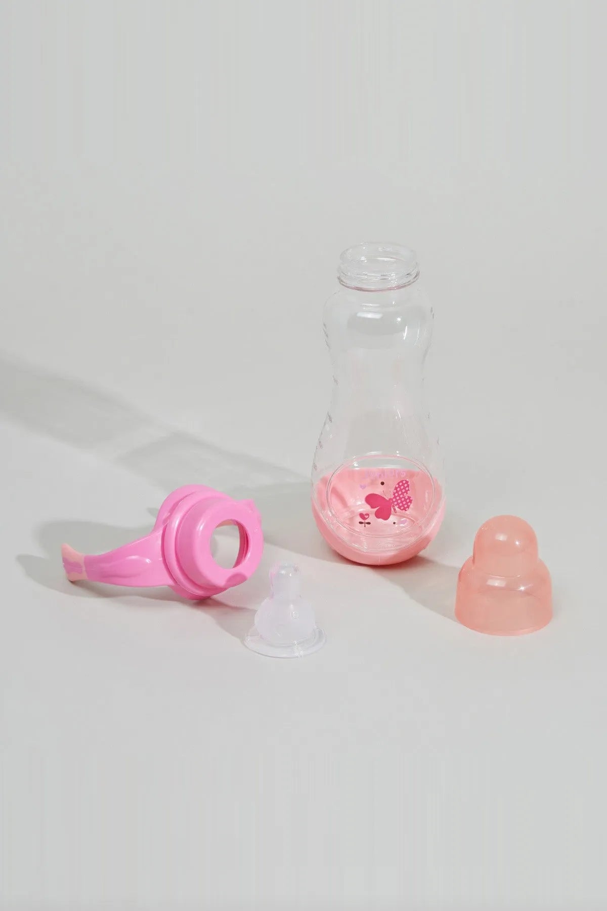 Pink spout cover and clear baby bottle with pink printed hearts, plus spare nipple