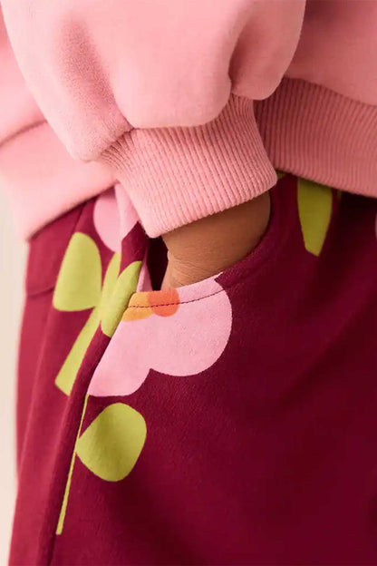 Burgundy kids pants with elastic waist and colorful flower print, close-up