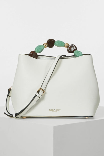 White bucket handbag with beaded handle, adjustable shoulder strap, gold-tone hardware