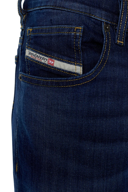 Blue denim jeans close-up of front pocket with logo patch and contrast stitching
